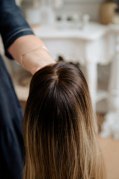 woman holding a dark hair topper with bailage 